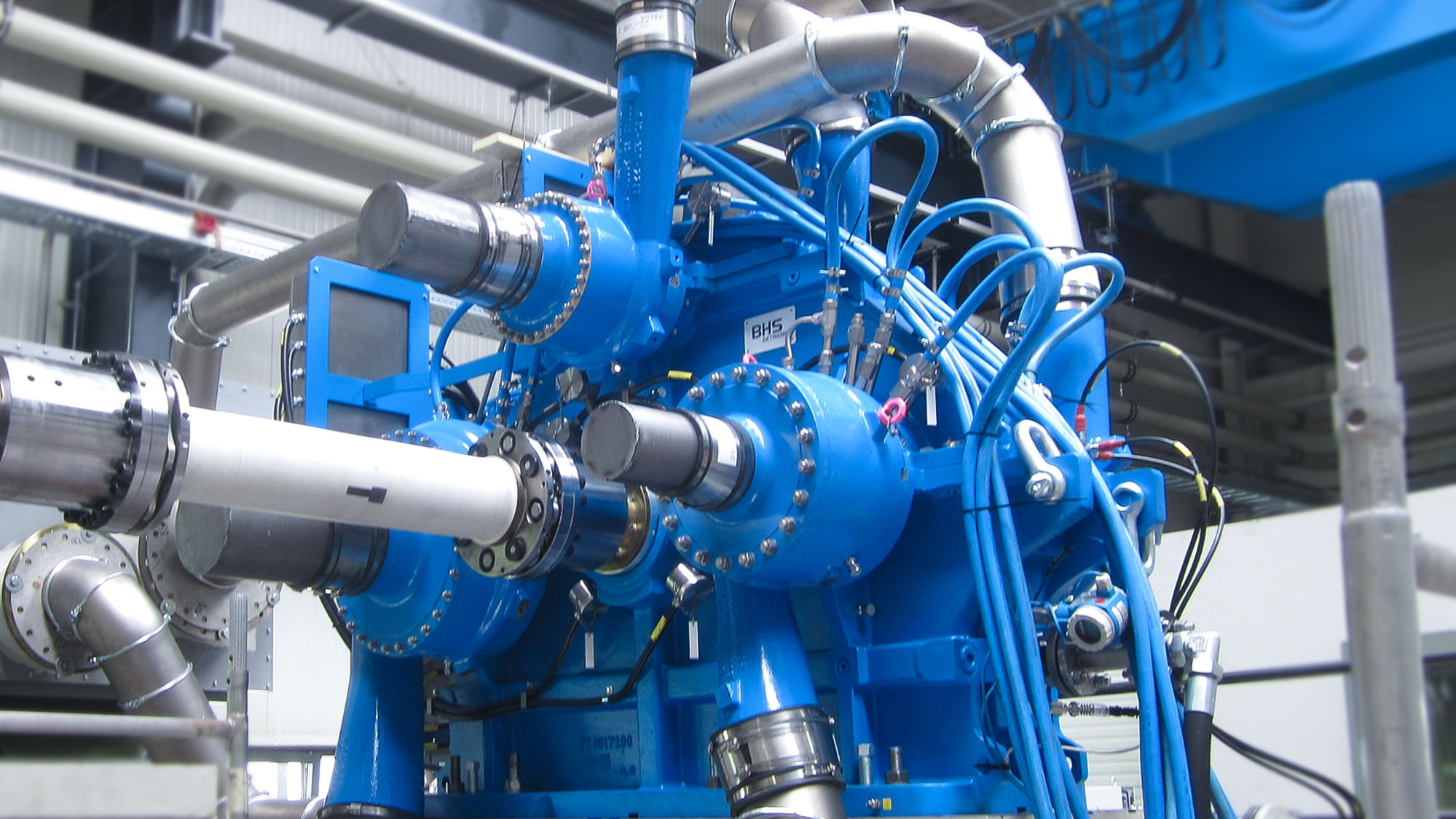 Shown is a blue integrally geared cntrifugal compressor with gray process gas lines on the test field.