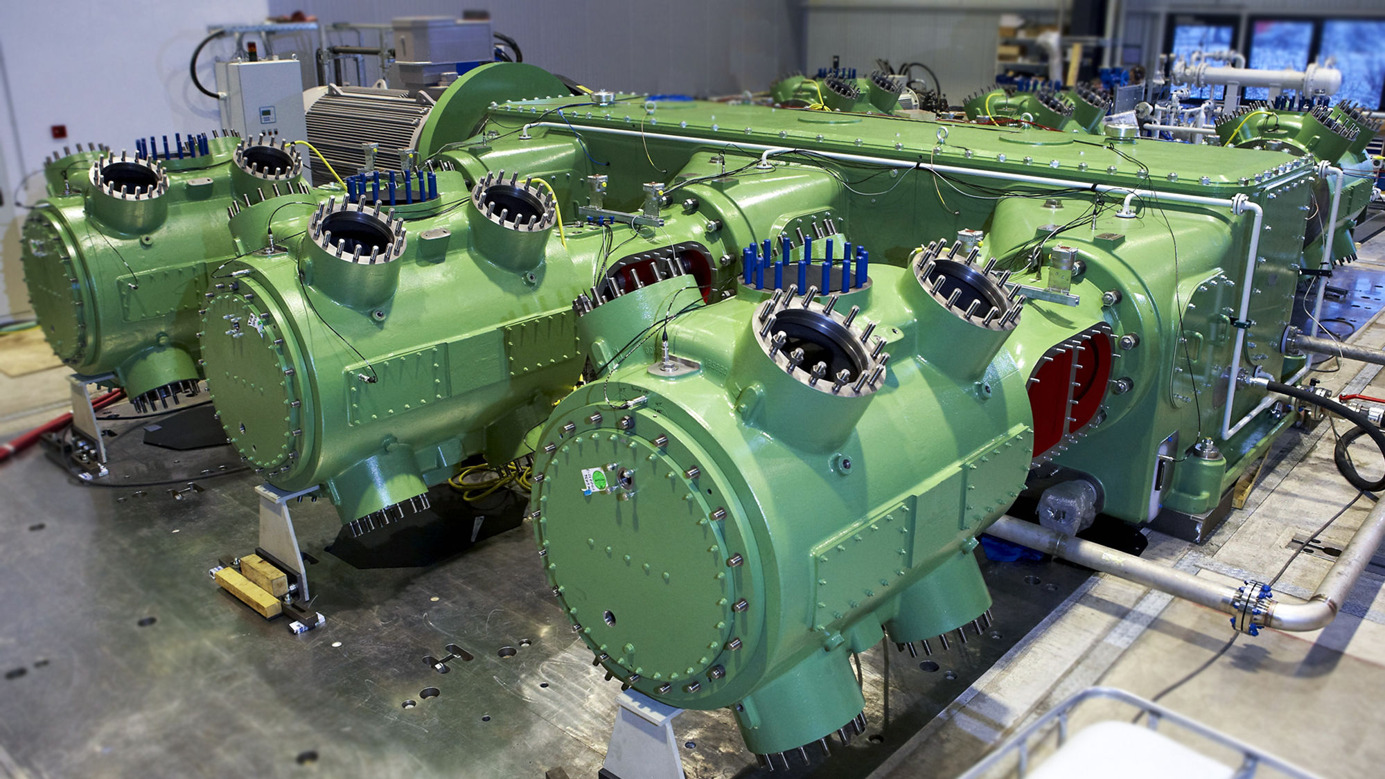 A green 6-crank reciprocating compressor of boxer design can be seen on the test field.