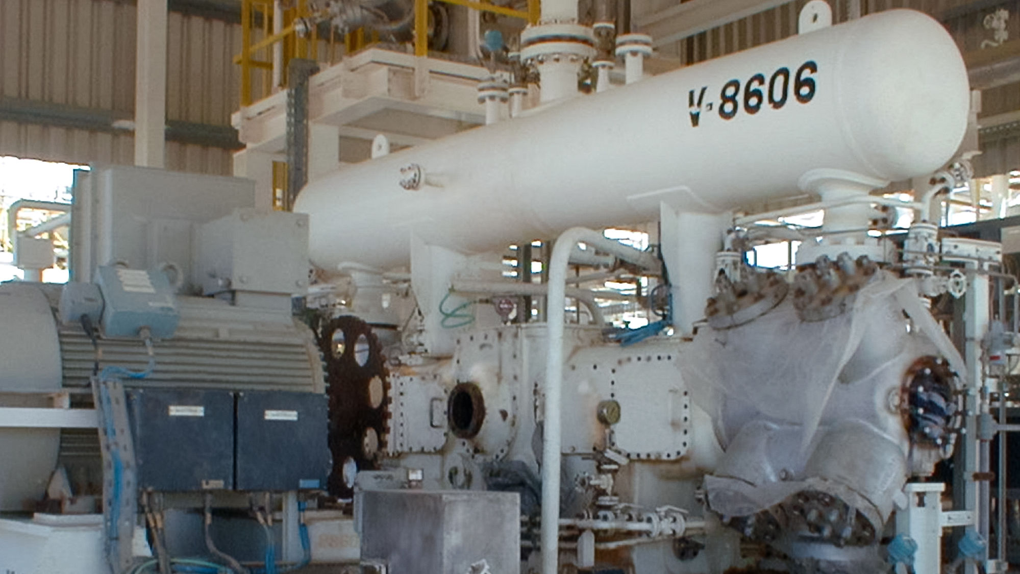 A white, high-speed reciprocating compressor in boxer design with pulsation tank, motor as well as flywheel can be seen. The photo was taken during maintenance of the off-gas compressor at the customer's plant.