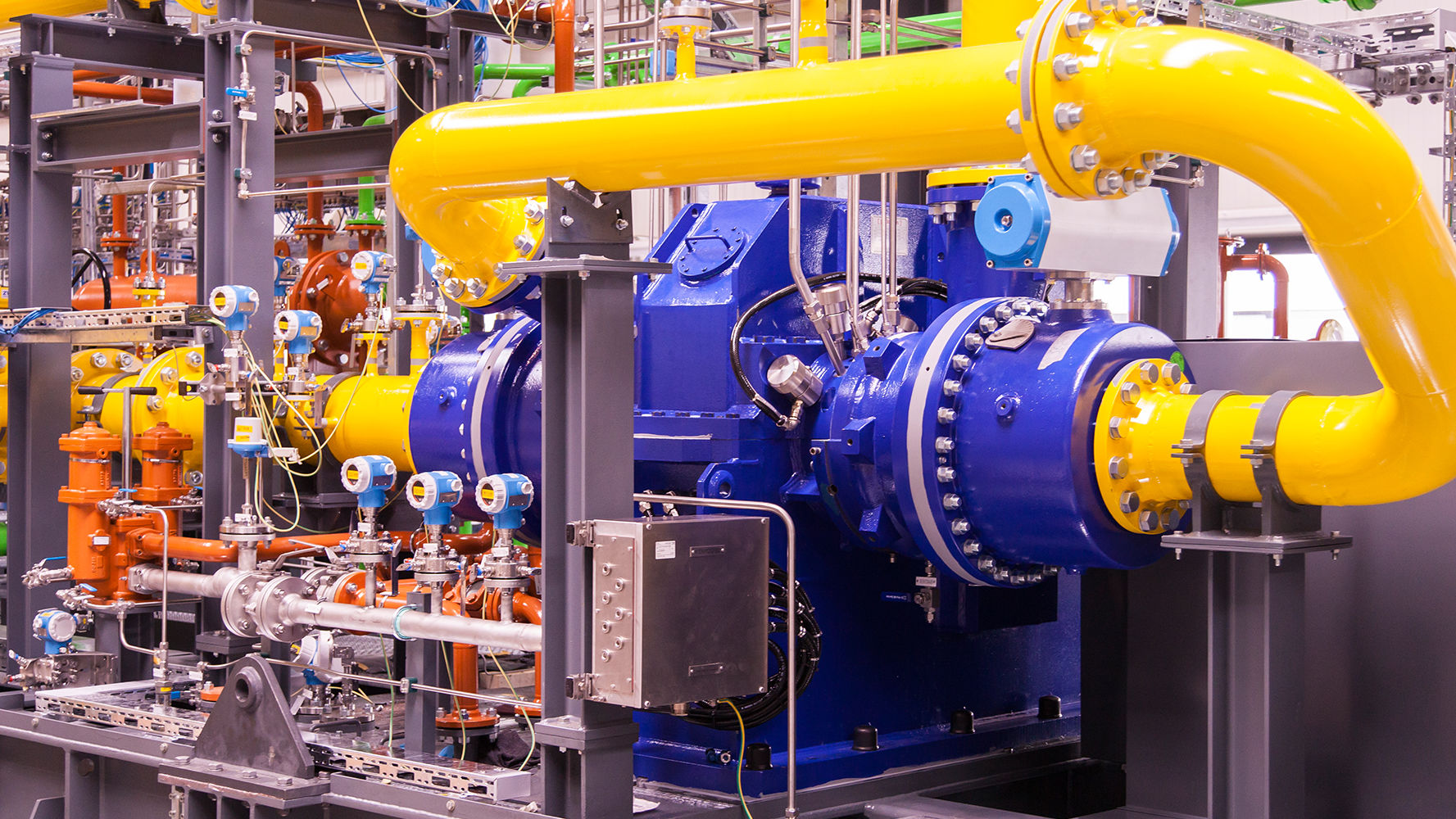 A blue 2-stage integrally geared centrifugal compressor with yellow process gas lines and measuring equipment is shown, installed on a skid.