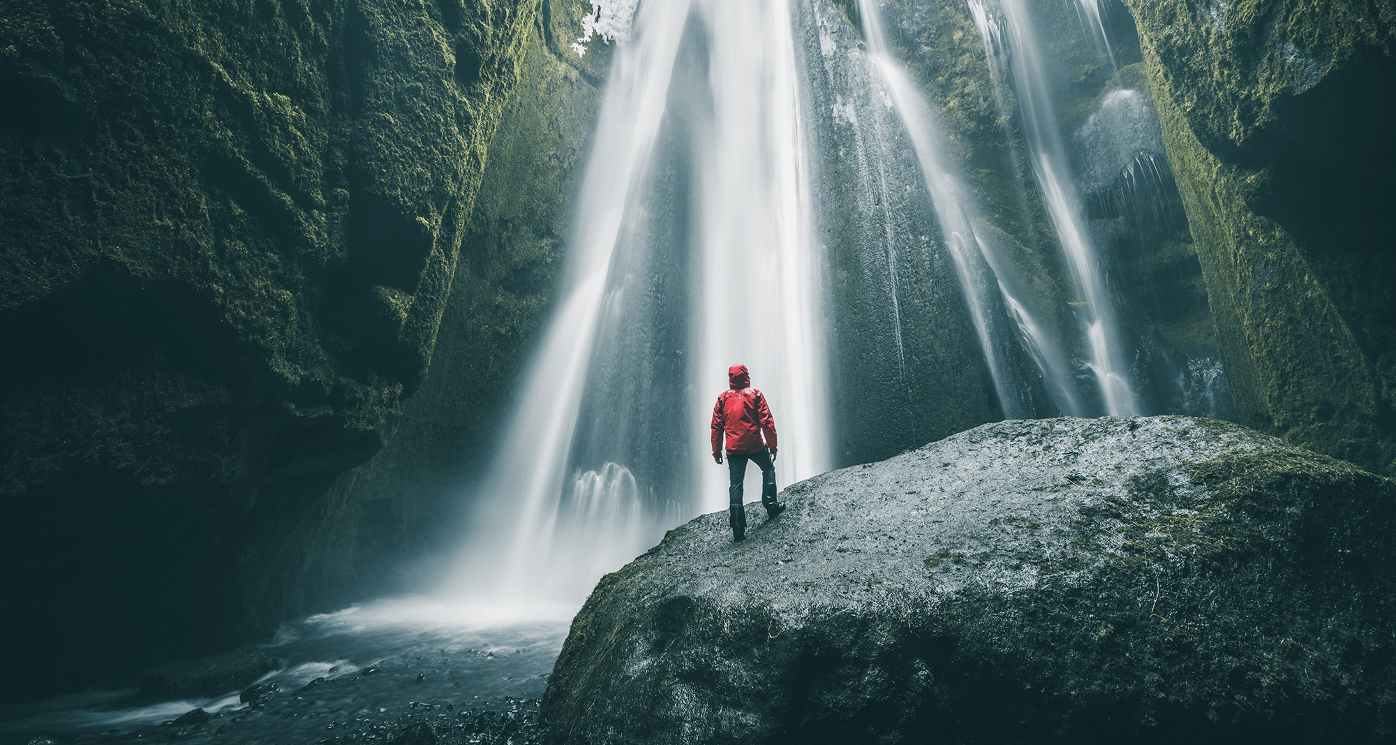 [Translate to Englisch:] man in front of waterfall